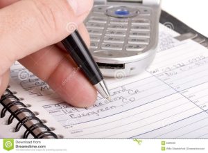 Writing In Address Book With Cell Phone Royalty Free Stock Photos